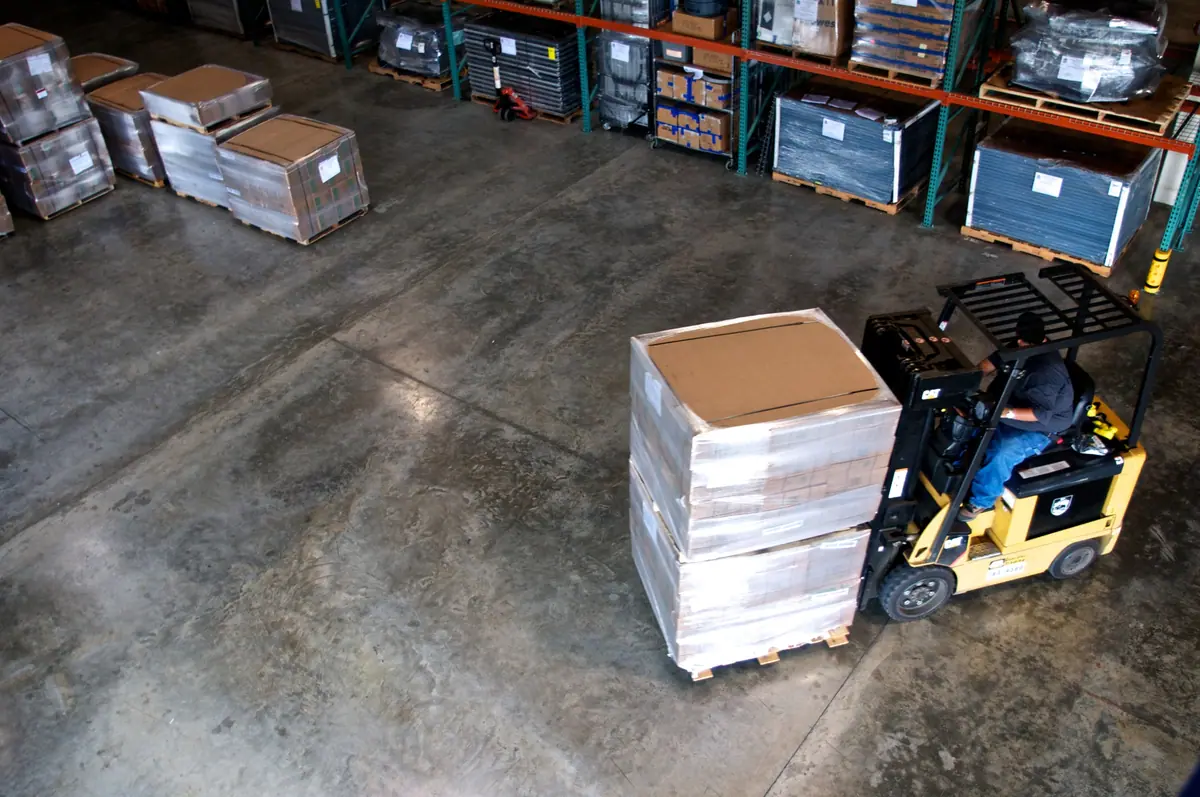 Depoda paleti taşıyan forklift ve pürüzsüz beton zemin